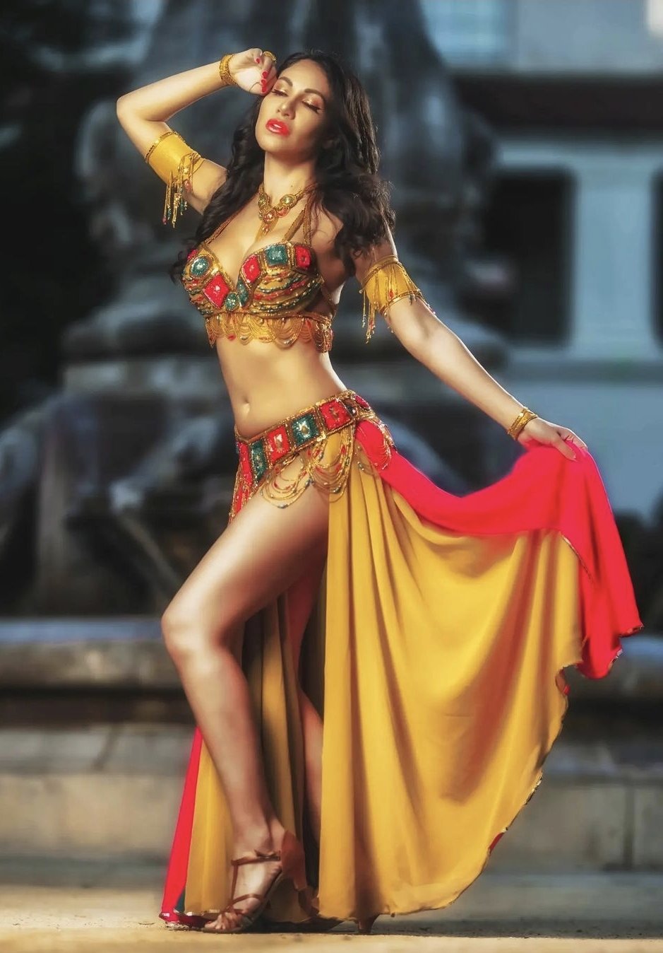 Erika in a gold and red belly dance costume beside a fountain